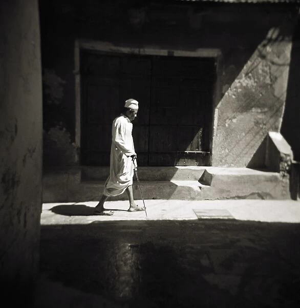 Image taken with a Holga medium format 120 film toy camera of a man in white djellaba caught in sunlight in backstreets of Stonetown, Zanzibar, Tanzania, East