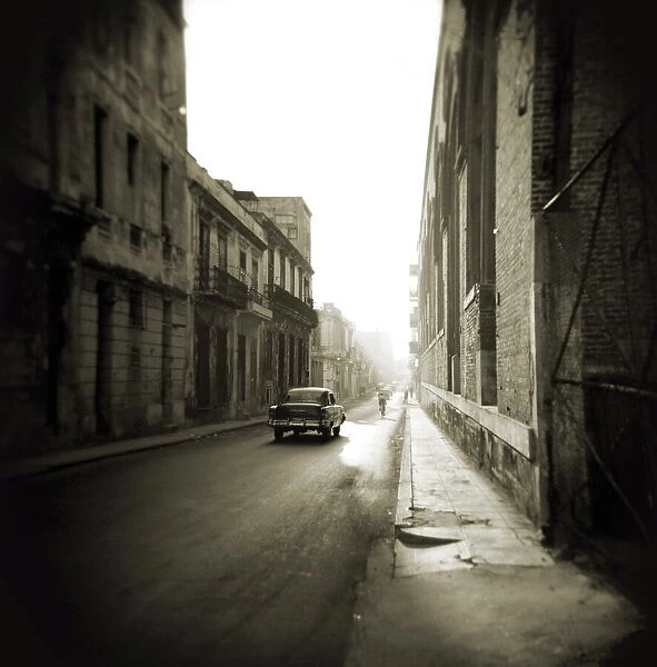 Image taken with a Holga medium format 120 film toy camera of early morning street scene with old American car, Havana, Cuba, West Indies