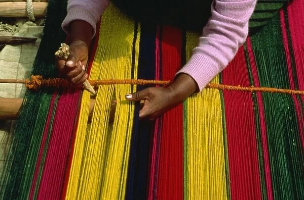 An Indian woman weaving a carpet in small village by Lake Titicaca, Bolivia