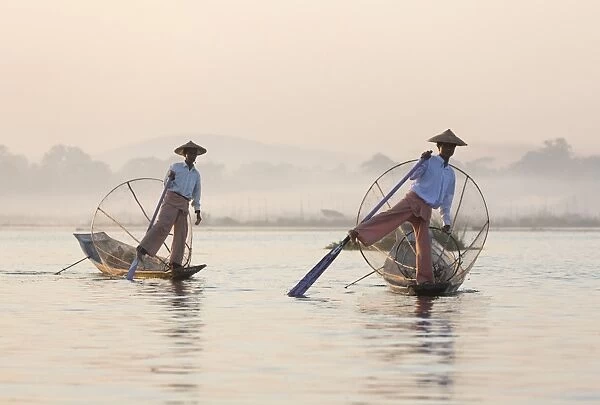 Intha leg rowing fishermen at dawn on Inle Lake who row traditional wooden boats using their leg and fish using nets stretched over conical bamboo frames, Inle Lake, Myanmar (Burma), Southeast Asia