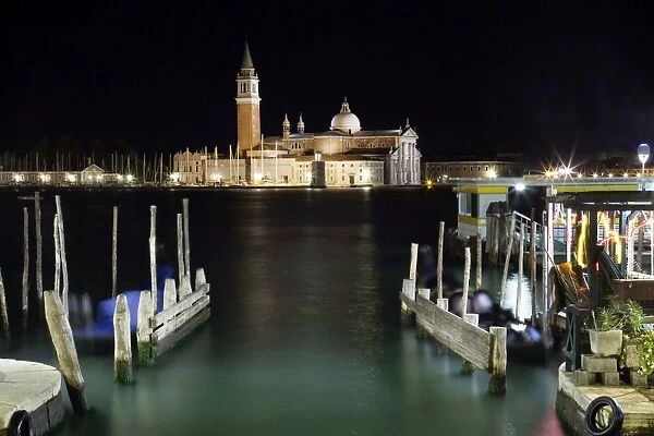 The island and church of San Georgio Maggiore at night with a boat dock in the foreground