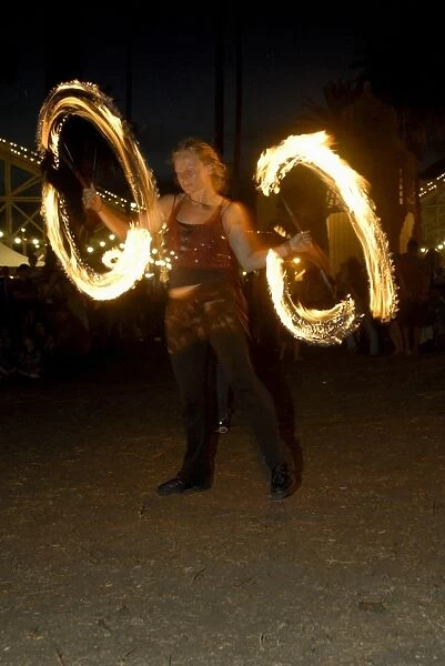 Juggler twirling rods during her performance, O Donnell Gardens, suburb of St. Kilda, Melbourne, Victoria, Australia