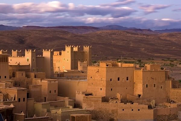 Kasbahs (fortified houses) bathed in evening sunlight with the Jbel Sarhro Mountains in the distance, Nkob, southern Morocco, Morocco, North