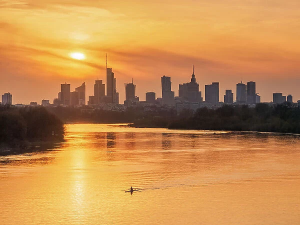 Kayaker and view over River Vistula towards City Centre Skyline at sunset, Warsaw, Masovian Voivodeship, Poland, Europe