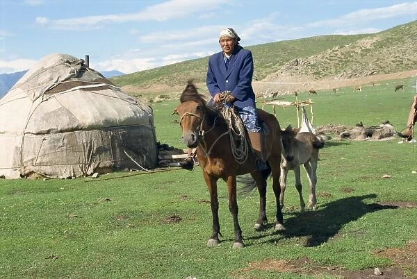 Kazak woman on horseback beside a yurt in the Altay mountains, north east Xinjiang
