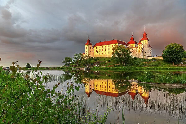 Lacko Castle and the reflection in the water at sunset, Kallandso island, Vanern lake, Vastra Gotaland, Sweden, Scandinavia, Europe