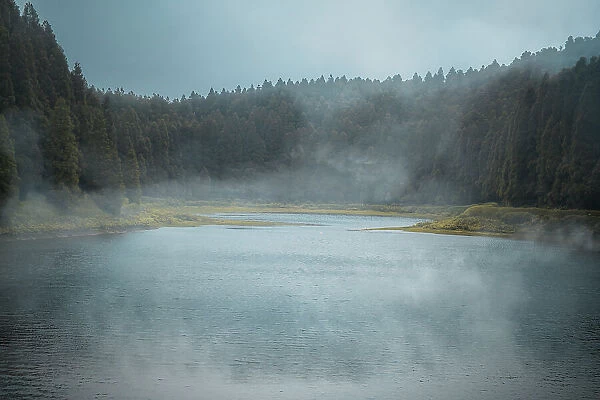 Lagoa do Eguas lake framed by a forest in a cloudy day with some low fog, Azores islands, Sao Miguel island, Portugal, Atlantic, Europe