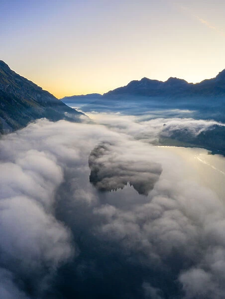 Lake Silvaplana and Sils hidden by the autumnal fog at dawn, aerial view by drone