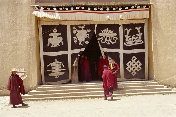 Lamas at monastery entrance, which is covered with a curtain depicting the sacred symbols of Buddhism, at Longki, south of Yushu in Qinghai