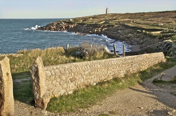 Landscape with typical stone wall with cross country walk and lighthouse at Cap Levi