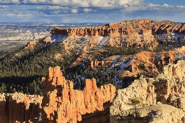 Late afternoon sun lights hoodoos and rocks through a cloudy sky in winter, Sunset Point, Bryce Canyon National Park, Utah, United States of America, North America