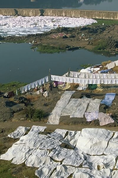 Laundry drying by the Mula River, with foam from detergent pollution beyond