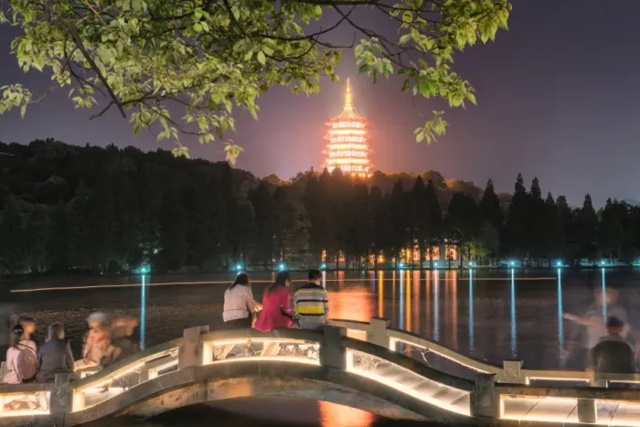 Framed Print : Leifeng Pagoda with visitors sitting on railings of an illuminated stone arch bridge at West Lake, Hangzhou, Zhejiang, China, Asia Framed Print : Leifeng Pagoda with visitors sitting on railings of an illuminated stone arch bridge at West Lake, Hangzhou, Zhejiang, China, Asia