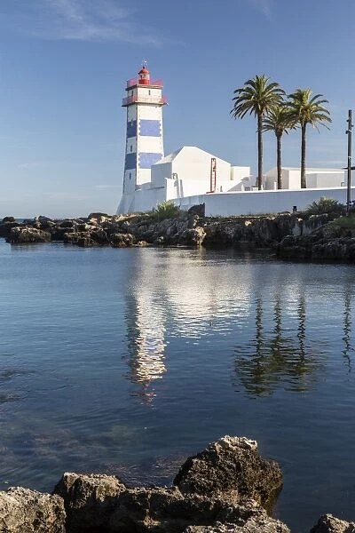 The lighthouse reflected in the blue water under the blue summer sky, Cascais, Estoril Coast