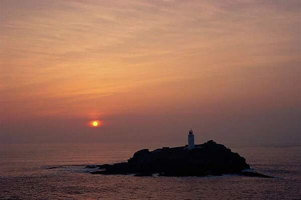 Lighthouse on rock in the sea at sunset at Godrevy Point, Cornwall, England