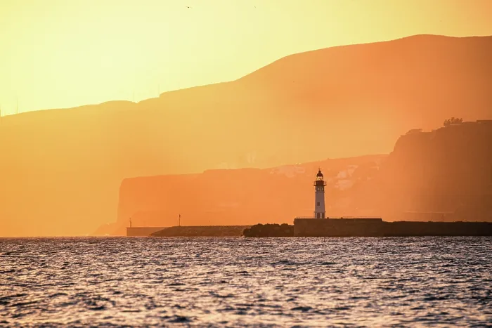 Framed Print : A lighthouse stands against golden coastal cliffs in AlmerAa, Spain, as the sunset casts a warm glow over the sea and landscape Framed Print : A lighthouse stands against golden coastal cliffs in AlmerAa, Spain, as the sunset casts a warm glow over the sea and landscape