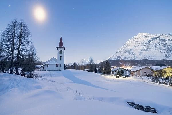 Lights of dusk on Chiesa Bianca and alpine village covered with snow, Maloja Pass
