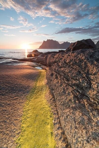 Lights of the midnight sun on the rocks surrounding the blue sea, Uttakleiv, Lofoten Islands