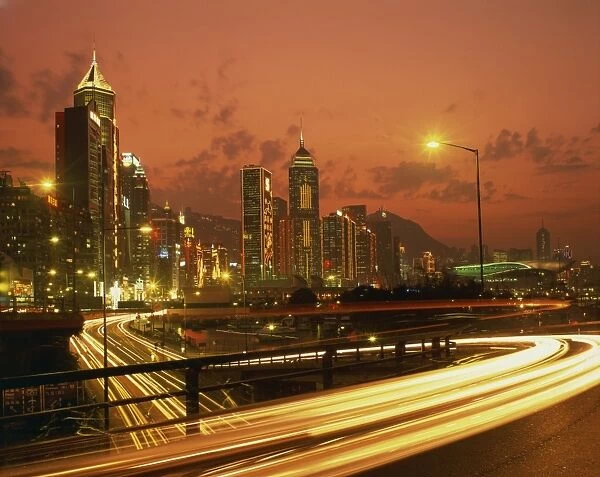 Lights on skyscrapers and traffic trails in the financial district of Hong Kong at sunset