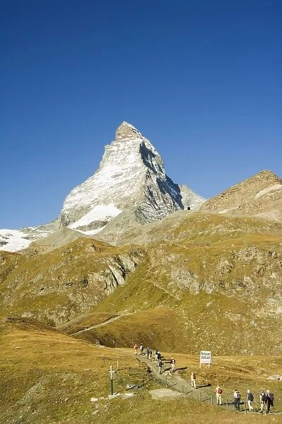 Line of hikers walking on trail near the Matterhorn