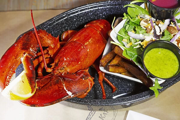 A lobster dinner served with salad, sauces and French fries in Barrington, Nova Scotia