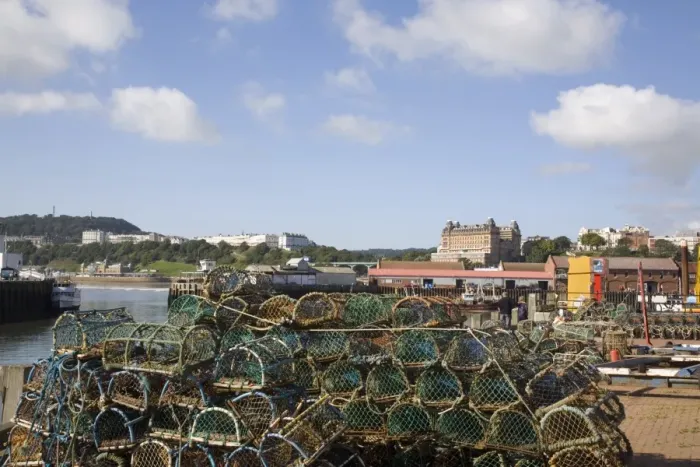 Framed Print : Lobster pots by Old Harbour in South Bay with hotels on South Cliff beyond Framed Print : Lobster pots by Old Harbour in South Bay with hotels on South Cliff beyond
