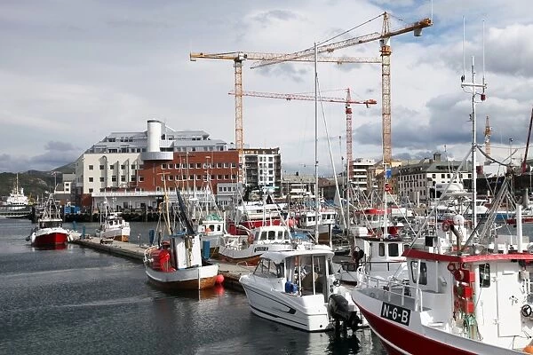 Local fishing boats and cranes working on new library site for North Norway, Bodo harbour north of the Arctic Circle, Nordland, Norway, Scandinavia, Europe