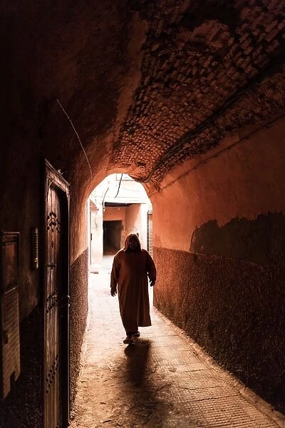 Local man dressed in traditional djellaba walking through archway in a street in the Kasbah