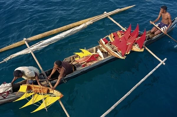 Local men transport model boats by canoe to market