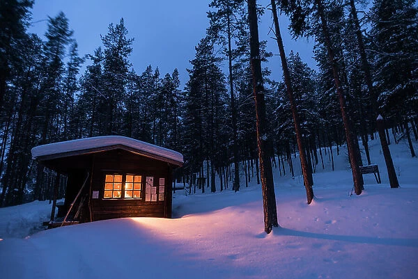 Log cabin with fire inside, winter, Lemmenjoki National Park, Finland, Europe