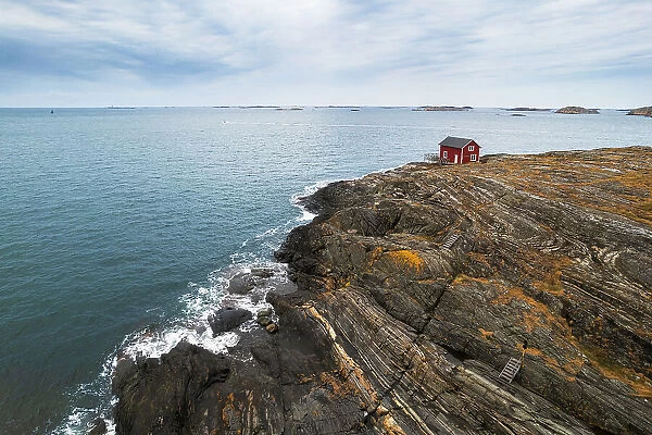 Lone red house surrounded by sea on top of a cliff of a rocky island, Bohuslan, Vastra Gotaland, West Sweden, Sweden, Scandinavia, Europe