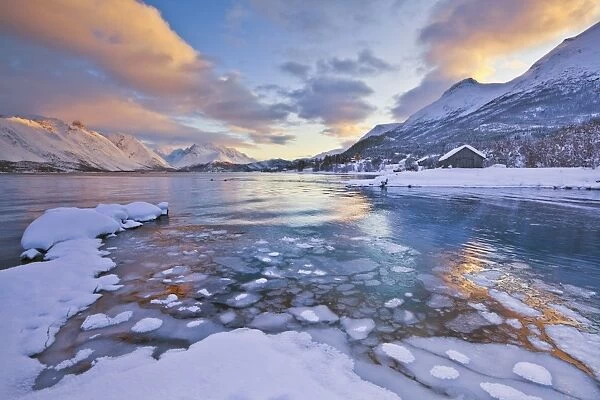 Looking across the frozen sea of Ullsfjord from Sjursnes, towards the Southern Lyngen Alps, at sunset, Troms, Norway, Scandinavia, Europe