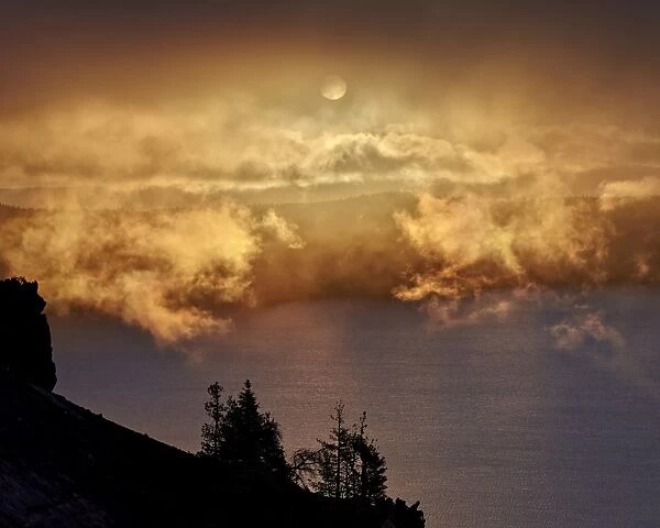 Low clouds glowing orange at sunrise, Crater Lake National Park, Oregon, United States of America, North America