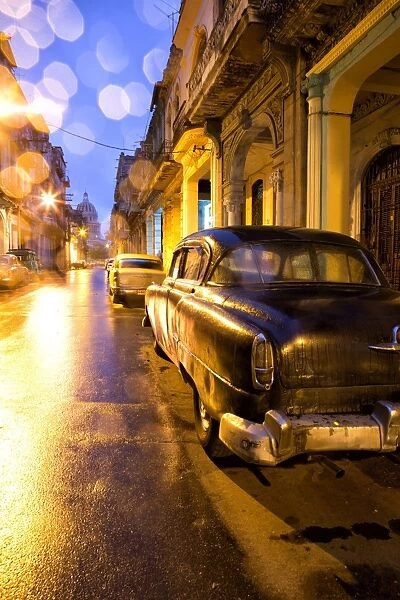 Low light view along a street towards The Capitolio with street lights reflecting in the wet tarmac and wet car bodywork after rain, Havana Centro, Havana, Cuba, West Indies, Central America