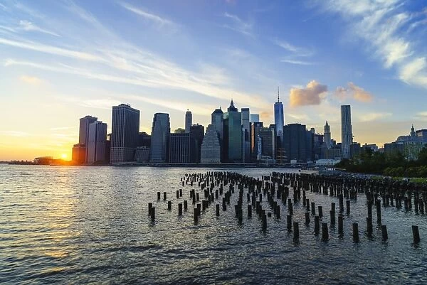 Lower Manhattan skyline at sunset, the remains of old warehouse pilings in the foreground, New York, United States of America, North America