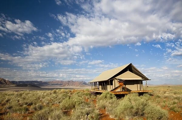 One of the luxury tents set in a magnificent landscape of orange sand dunes and sandstone mountains at Wolwedans Dune Camp in the Namib Rand game reserve, Namib Naukluft Park, Namibia, Africa