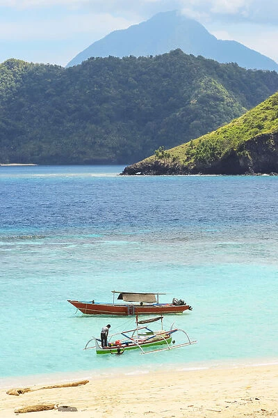 Mahoro Island beach with tour boats and a volcano far beyond on Siau, Mahoro, Siau, Sangihe Archipelago, North Sulawesi, Indonesia, Southeast Asia, Asia