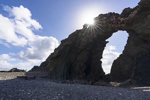 Majestic Arco del Juradonatural arch lit by sun on Pena Horadada beach, Betancuria