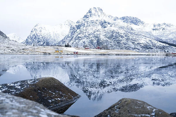 Majestic mountain peaks mirrored in the icy sea in winter, Flakstadpollen, Flakstadoya, Nordland, Lofoten Islands, Norway, Scandinavia, Europe