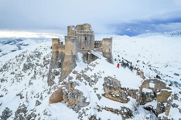 Man admiring the snowy medieval castle of Rocca Calascio after heavy snowfall, Rocca Calascio, Gran Sasso and Monti della Laga National Park, L'Aquila province, Abruzzo region, Apennines, Italy, Europe