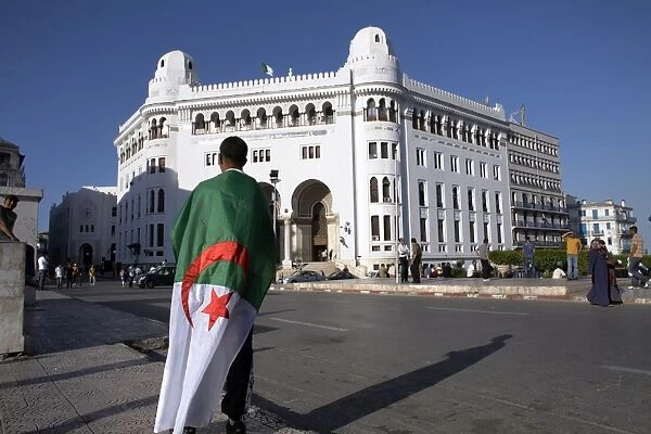 A man with an Algerian flag stands in front of Grande Poste in Algiers