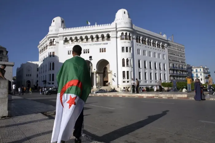 Framed Print : A man with an Algerian flag stands in front of Grande Poste in Algiers Framed Print : A man with an Algerian flag stands in front of Grande Poste in Algiers