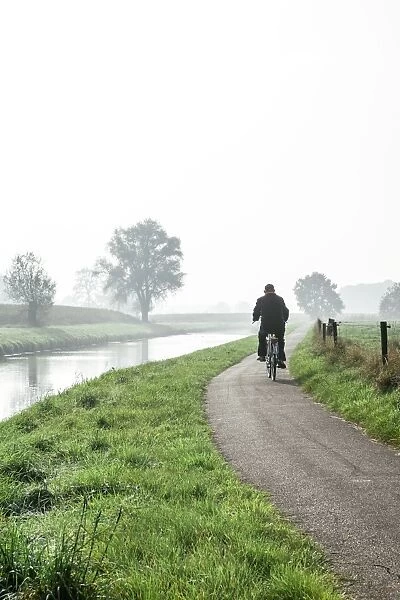 Man cycling on countryside cycle path next to the River Mark in autumn, Breda, North Brabant, The Netherlands (Holland), Europe