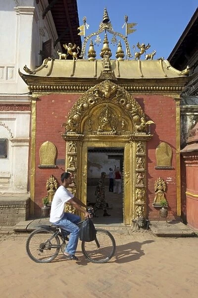 Man cycling past the Golden Gate, Sun Dhoka, in Durbar Square, Bhaktapur