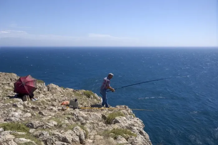 Framed Print : A man fishes from the tall cliffs of Cabo de Sao Vicente