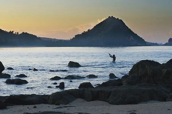 Man fishing with a net at sunrise on Kuta Beach, Lombok, Indonesia, Southeast Asia, Asia