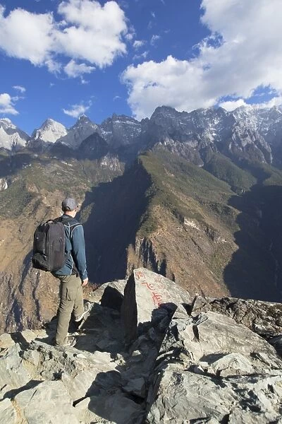 Man hiking in Tiger Leaping Gorge, UNESCO World Heritage Site, with Jade Dragon Snow Mountain