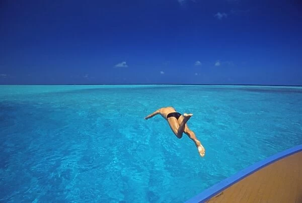 Man jumping into tropical sea from deck, Maldives, Indian Ocean, Asia