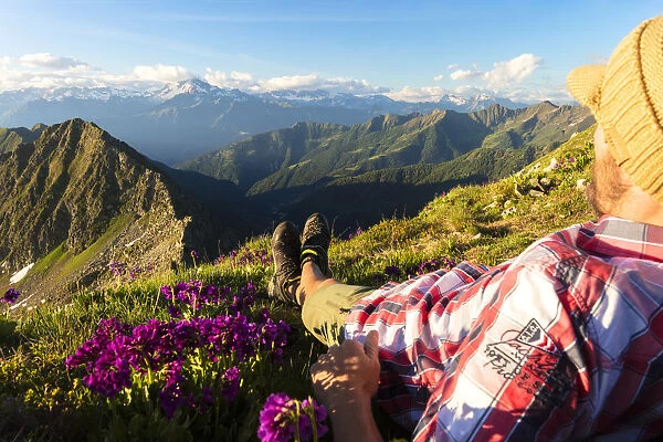 Man lying down on top of Monte Azzarini looks to Monte Disgrazia and Monte Pedena