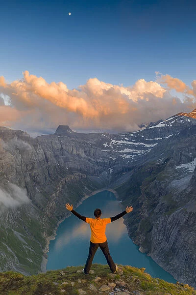 Man with outstretched arms enjoying sunset over lake Limmernsee standing on top of rocks